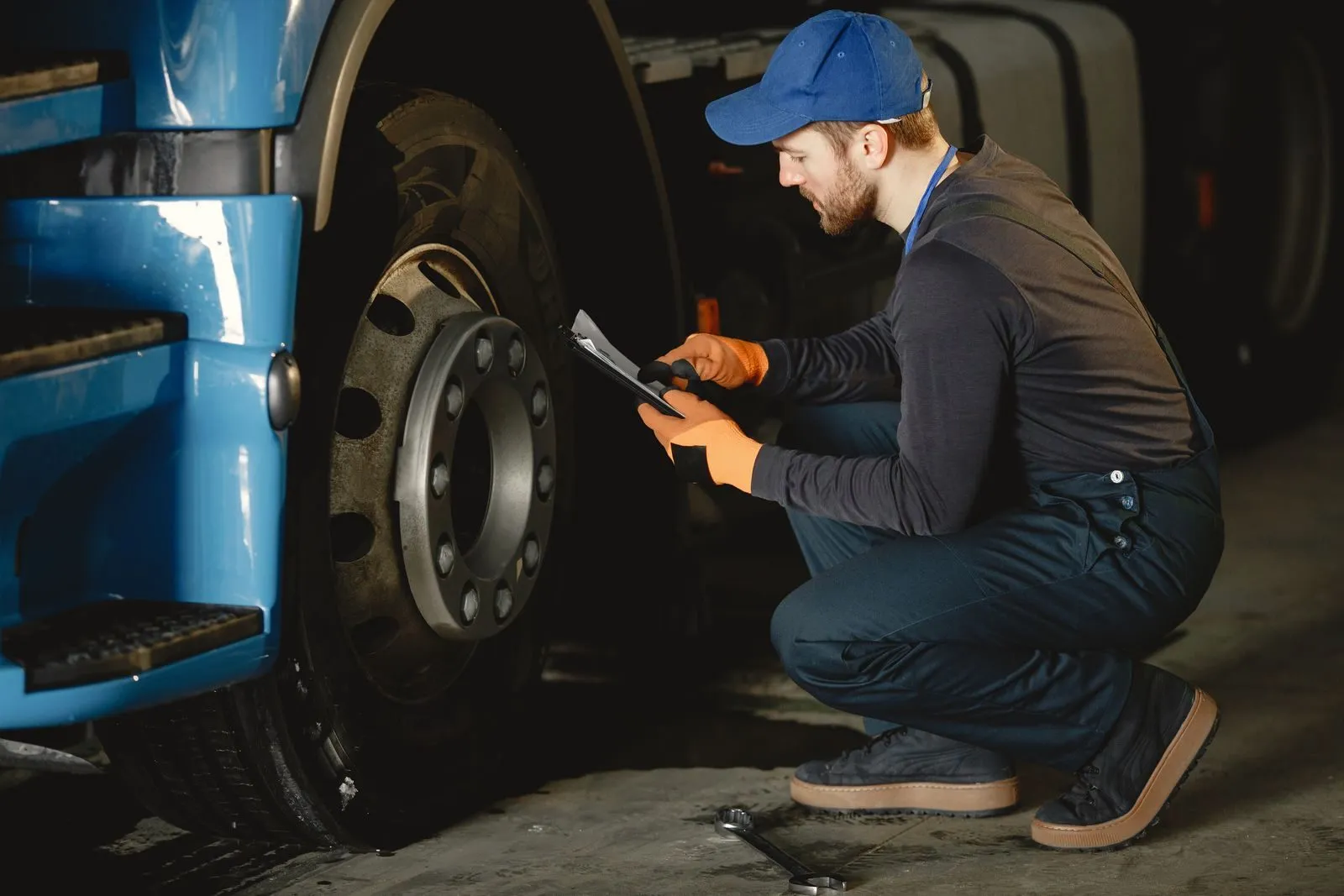 A mechanic inspecting a truck wheel and checking his notes